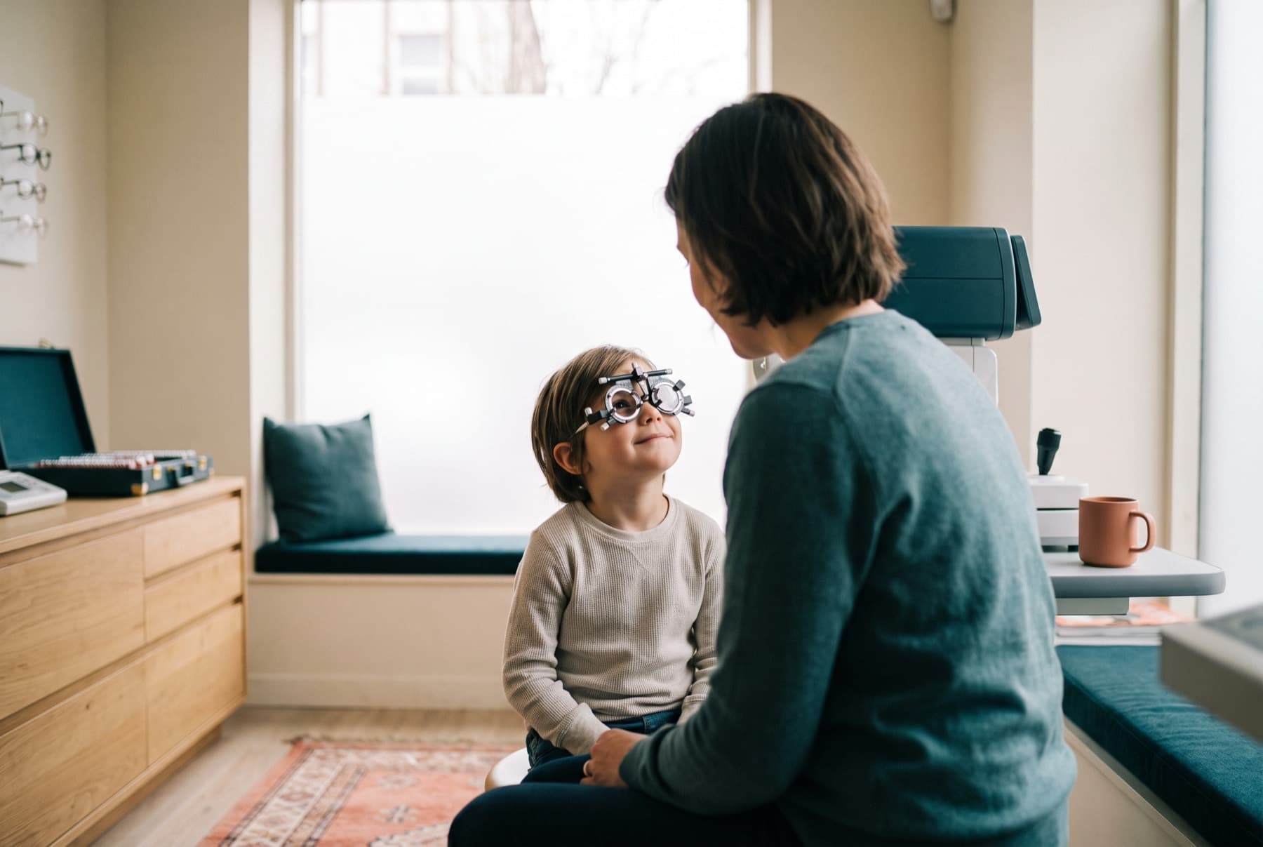 A young child trying on a trial frame with a parent nearby during a calm myopia exam